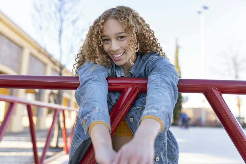 pretty curly-haired happy smiling woman leaning on a railing without gerd